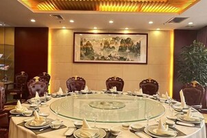 A round dining table with chairs, set for a meal, in a room with a framed painting on the wall.