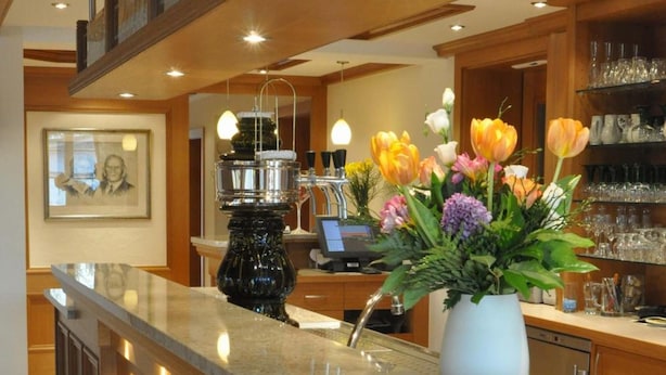 A kitchen with a granite countertop, a vase of flowers, and wooden cabinets. - Gasthof Engel (Appenweier)