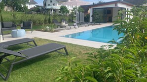 A pool area with lounge chairs, a small round table, and umbrellas. - Gasthof Engel (Appenweier)