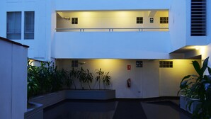 A modern building with a courtyard, featuring a fire extinguisher, a water fountain, and potted plants. - The Comfortable Flat Miraflores (Lima)