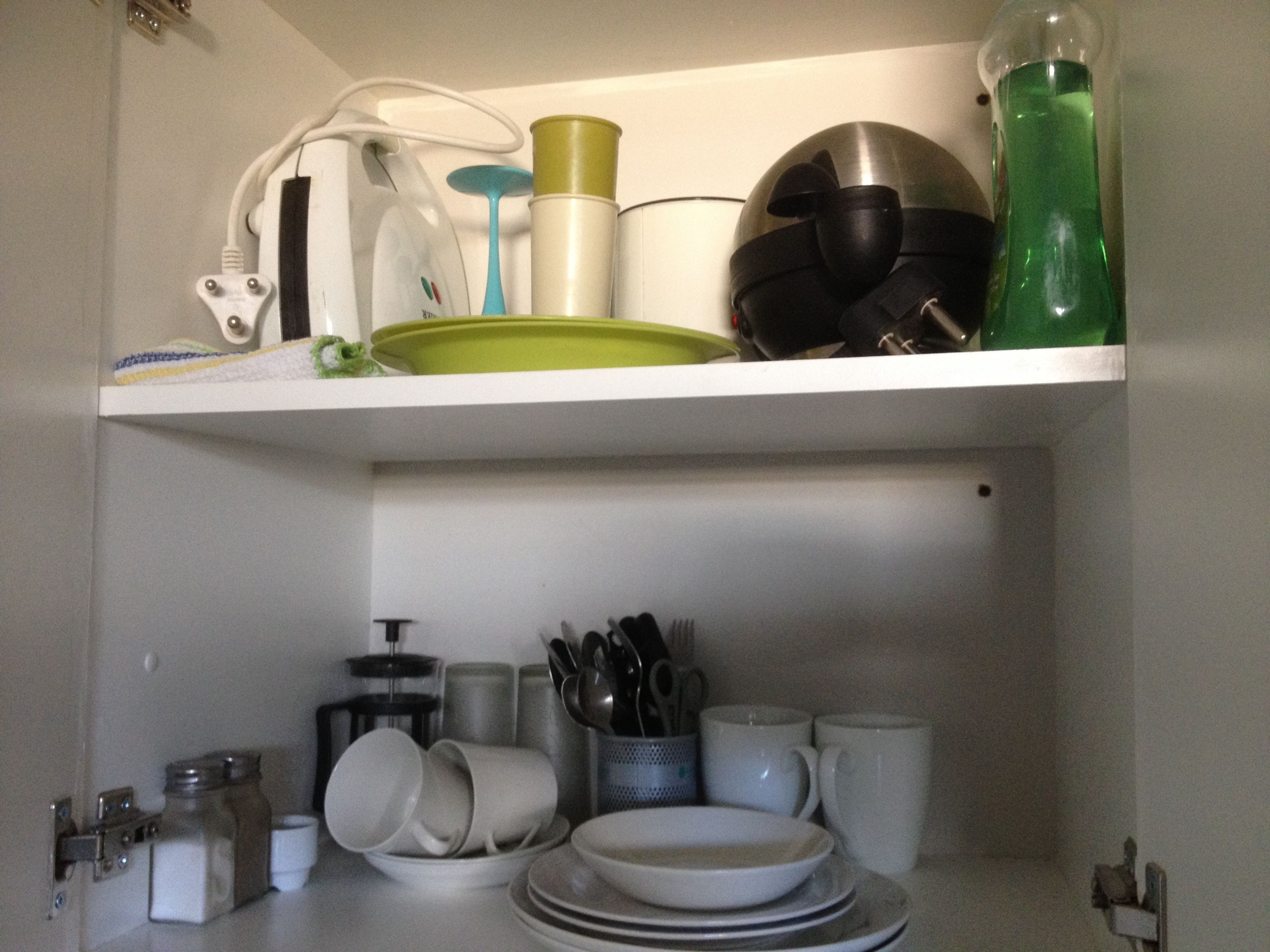 A kitchen shelf with various dishes, utensils, and containers.