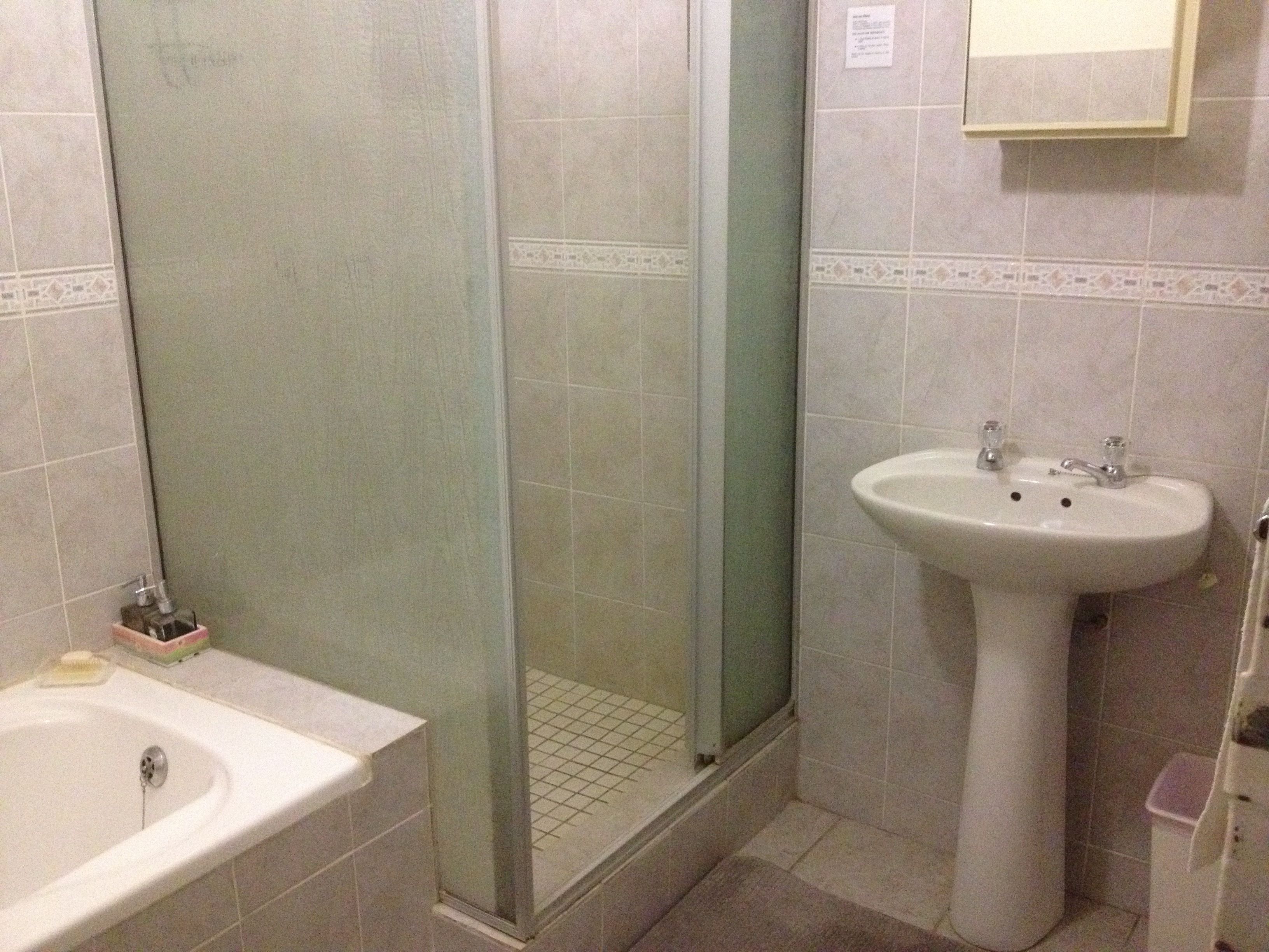 A bathroom with a shower, sink, and a mirror.