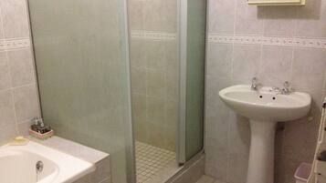 A bathroom with a shower, sink, and a mirror.