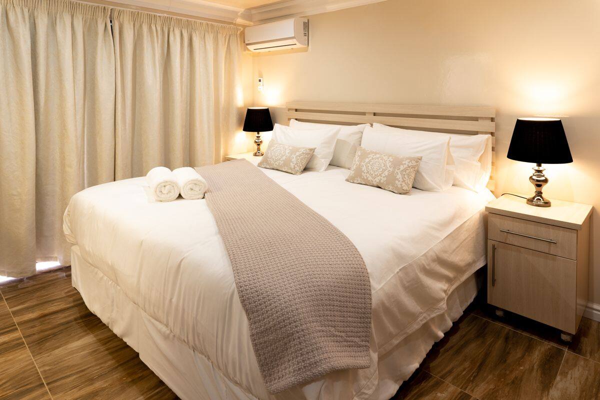 Ein Hotelzimmer mit einem großen Bett, zwei Nachttischlampen, einem Nachttisch und einer Klimaanlage.