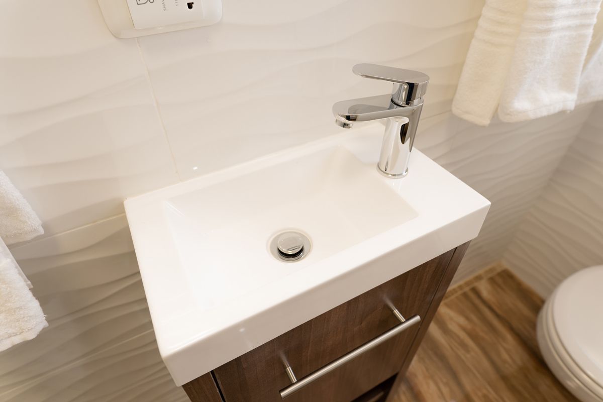 Une salle de bain avec un lavabo blanc, un robinet chromé et un meuble en bois.
