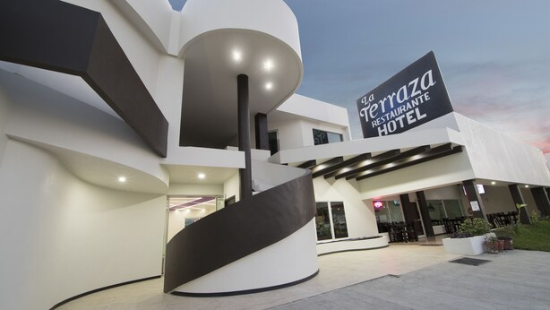 Un hotel moderno con una espiral destacada, un cartel grande que dice 'La Terrazza Restaurante Hotel' y un área de entrada bien iluminada.