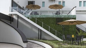 Un área de estar exterior moderna con un sendero curvo, una escalera y una pared verde con plantas.