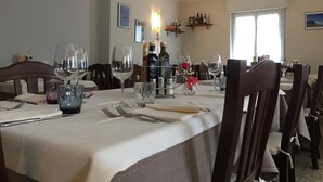 Una mesa de comedor dispuesta con copas de vino, cubiertos y una botella de vino.