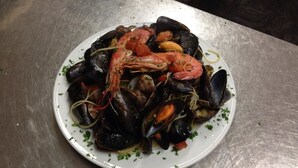 Un plato de mariscos que incluye mejillones, camarones y calamares, adornado con hierbas.