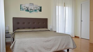Un dormitorio con una cama grande, una mesita de noche, una lámpara de pared y una puerta.