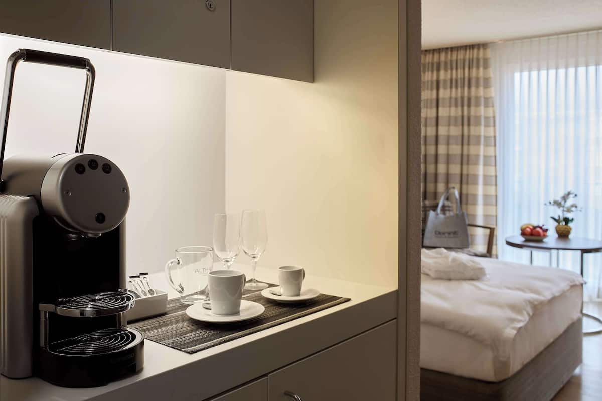 Et moderne hotelværelse med tekøkken, en seng, et lille bord med frugtskål og udsigt over værelset.