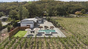 Propiedad residencial con piscina, mobiliario exterior y viñedo.