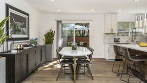 Una cocina moderna con comedor, que cuenta con un amplio ventanal, una isla integrada y vistas al exterior.