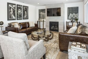 A modern living room with a leather sofa, a glass coffee table, and a fireplace. - Vineyard Villa (Calistoga)