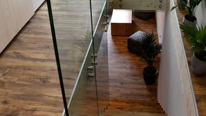 Ein modernes Schlafzimmer im Loft-Stil mit Wendeltreppe aus Glas, Holzboden und einem Bett mit weißer Bettwäsche.