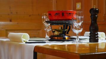 A table with a red teapot, two wine glasses, a pepper shaker, and a rolled-up napkin.