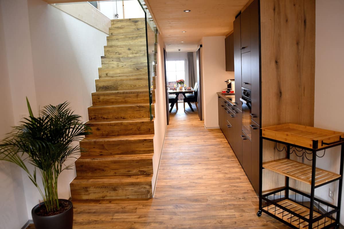 A wooden staircase leading to a dining area with a view of the outdoors.