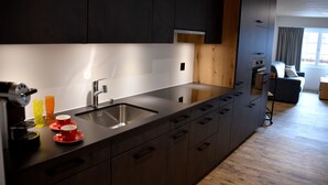 Eine moderne Küche mit dunklen Schränken, einer Edelstahl-Spüle und einer Holzausziehtafel.