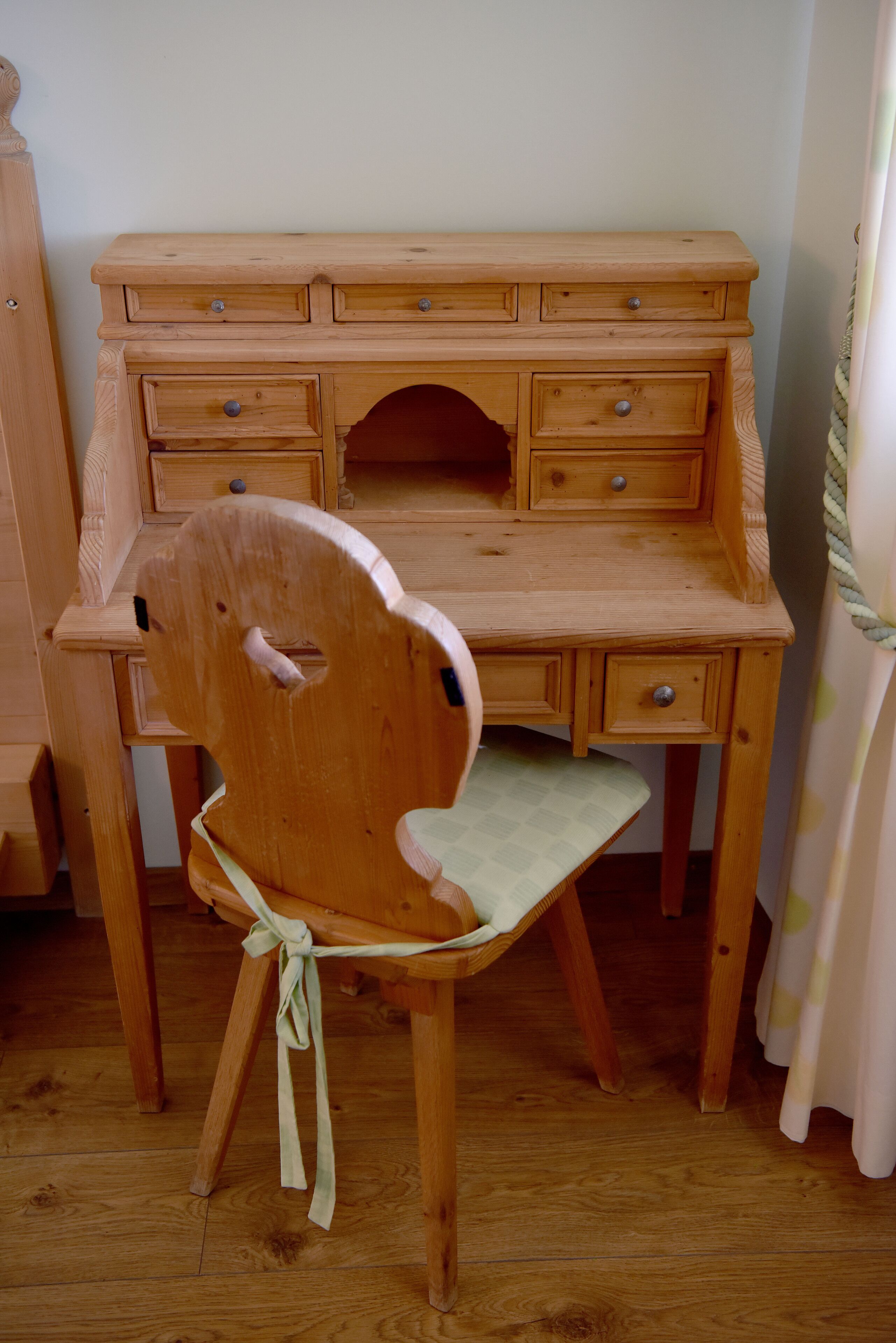 Un escritorio de madera con varios cajones y una silla con cojín.