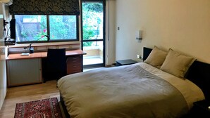A bedroom with a bed, a desk, and a window with a view of greenery. - Stone-house in the heart of Nicosia (Nicosia)
