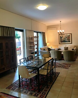 A living room with a glass-top dining table, chairs, a sofa, a ladder, and a chandelier. - Stone-house in the heart of Nicosia (Nicosia)
