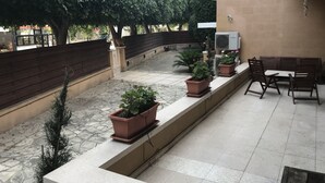An outdoor patio area with a low wall, potted plants, a bench, and an air conditioning unit. - Stone-house in the heart of Nicosia (Nicosia)