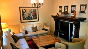 A living room with a sofa set, a wooden coffee table, a fireplace, and a chandelier. - Stone-house in the heart of Nicosia (Nicosia)