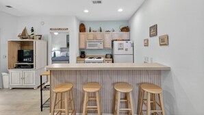 Une cuisine dotée d’un îlot central, de tabourets en bois, d’un four à micro-ondes, d’une cuisinière et de placards.