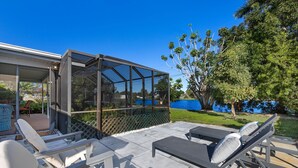 A patio with outdoor furniture, a glass enclosure, and a view of a body of water. - Naples Lake House. Bike to Beach. Pet Friendly (Naples)