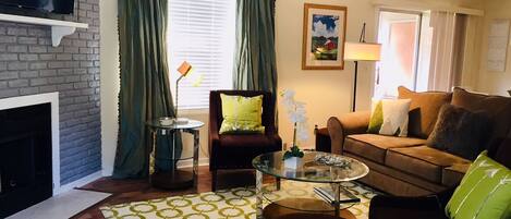 A living room with a fireplace, a television, a sofa, a coffee table, and a patterned rug.