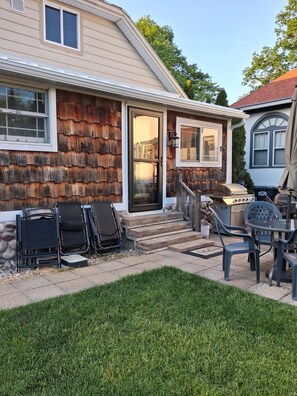 Une maison avec un porche à l’avant, un barbecue et du mobilier d’extérieur.