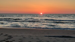 Una playa con el sol poniéndose sobre el océano.