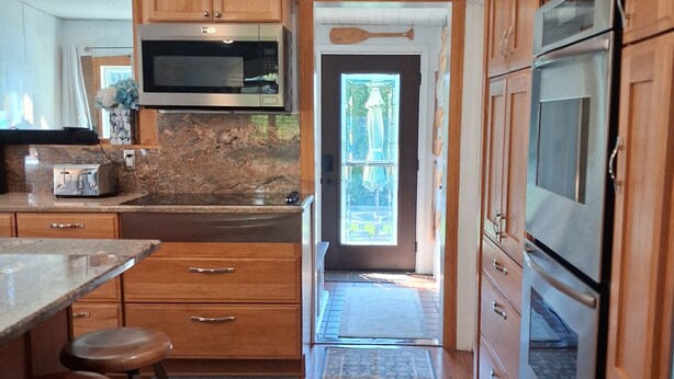 Una cocina con gabinetes de madera, un microondas, un horno y un lavamanos.