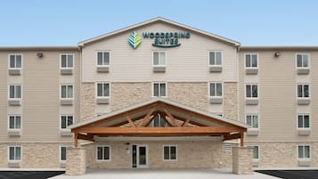A hotel with a stone facade, multiple windows, and a covered entrance.