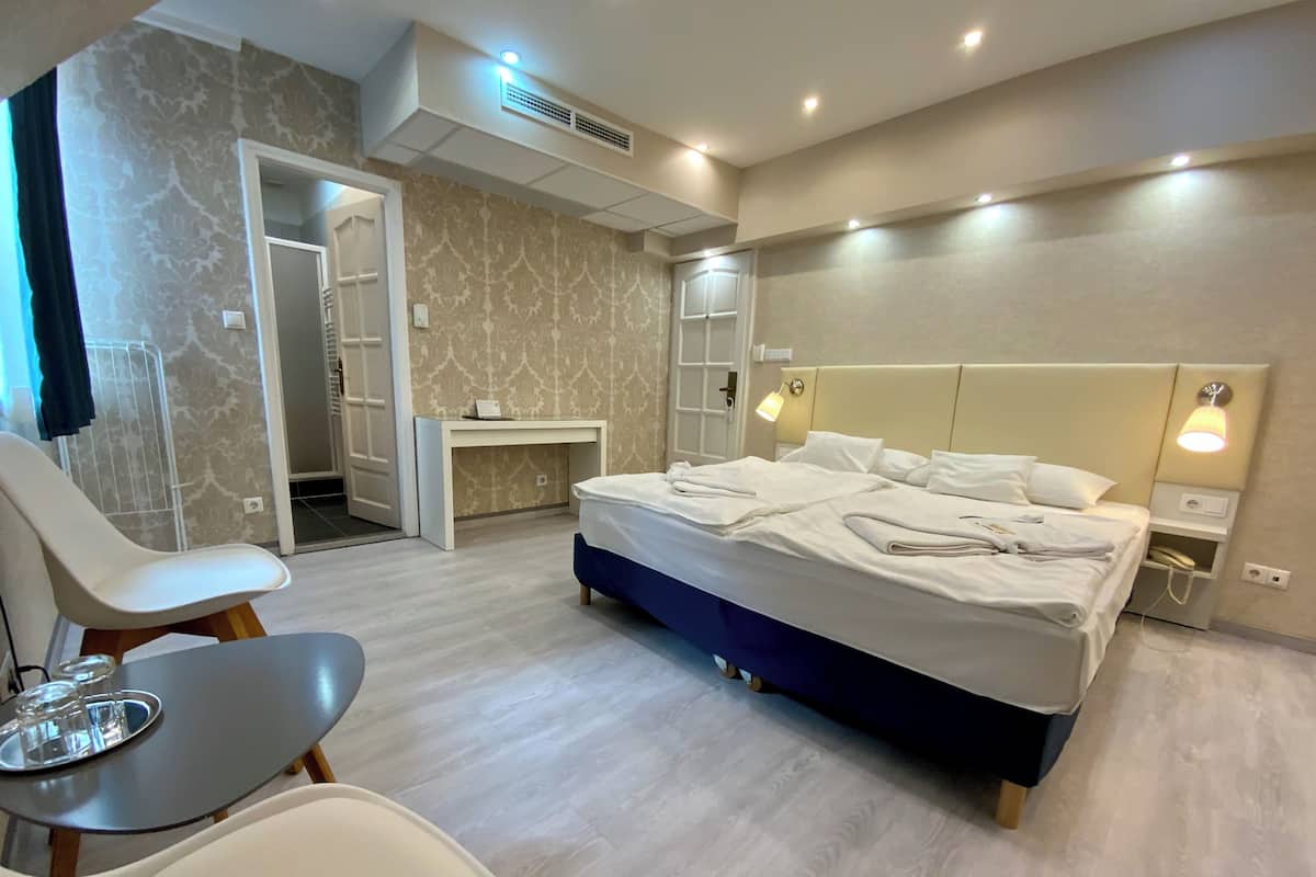 A modern hotel room with a large bed, bedside tables, a desk, and a chair.