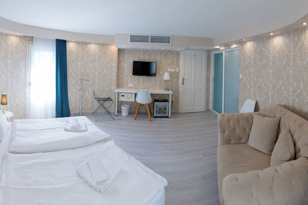 A hotel room with a bed, a desk, a TV, and a couch.