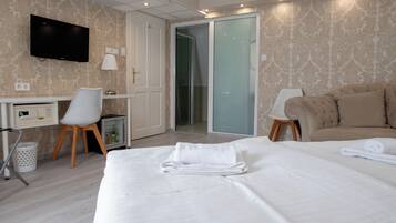 A hotel room with a bed, a desk, a chair, a television, and a sliding door to a bathroom.