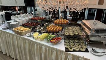 A buffet table with various food items, a chandelier, and a TV in the background.
