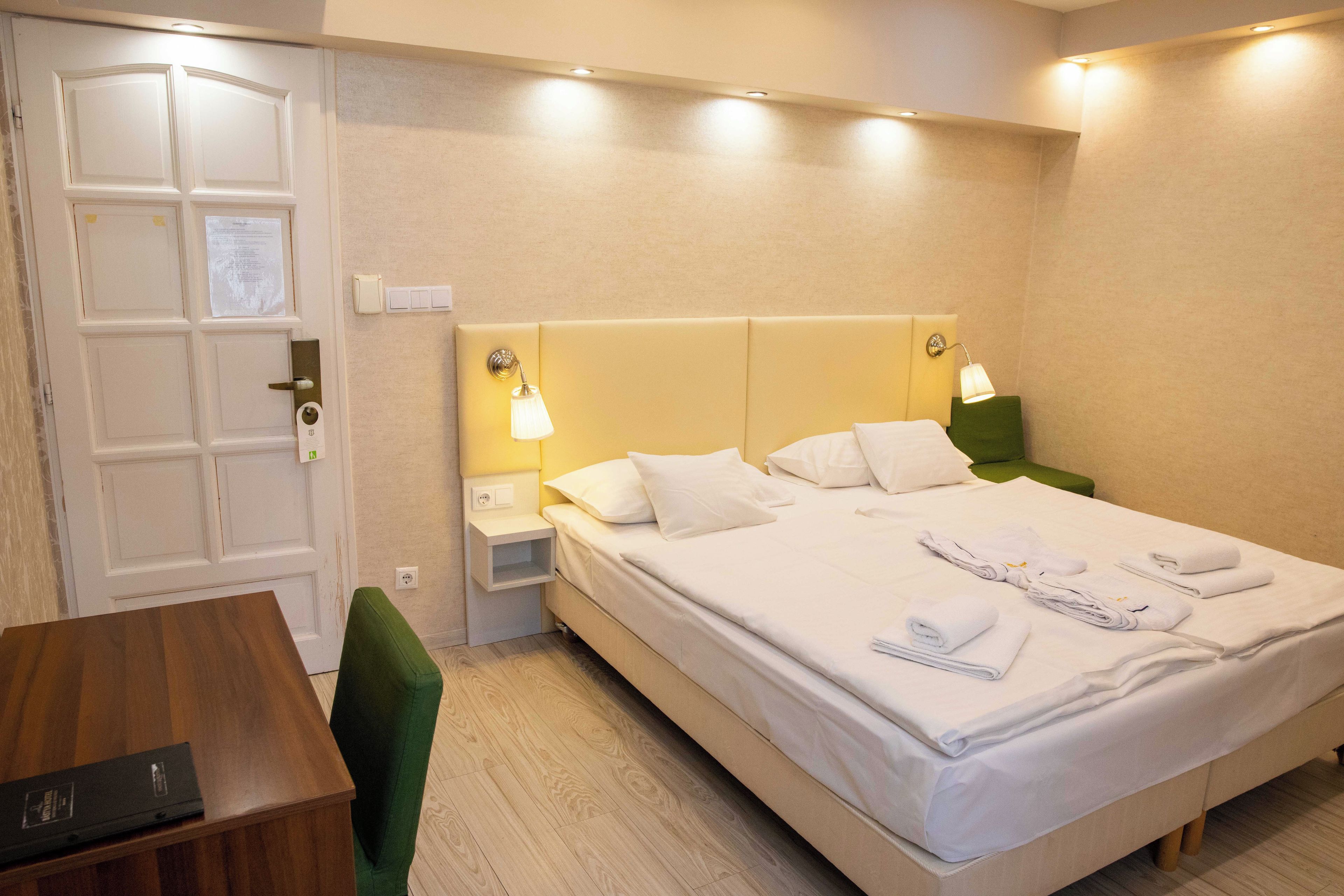Una habitación de hotel con cama, mesitas de noche, escritorio y silla.