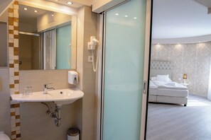 A modern bathroom with a sink, mirror, and hairdryer. - Bastya Wellness Hotel (Miskolc)