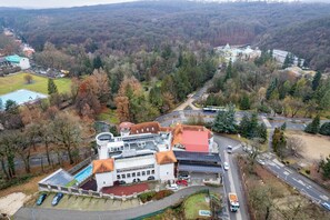 An aerial view of a campus with a swimming pool, parking area, and buildings surrounded by trees. - Bastya Wellness Hotel (Miskolc)