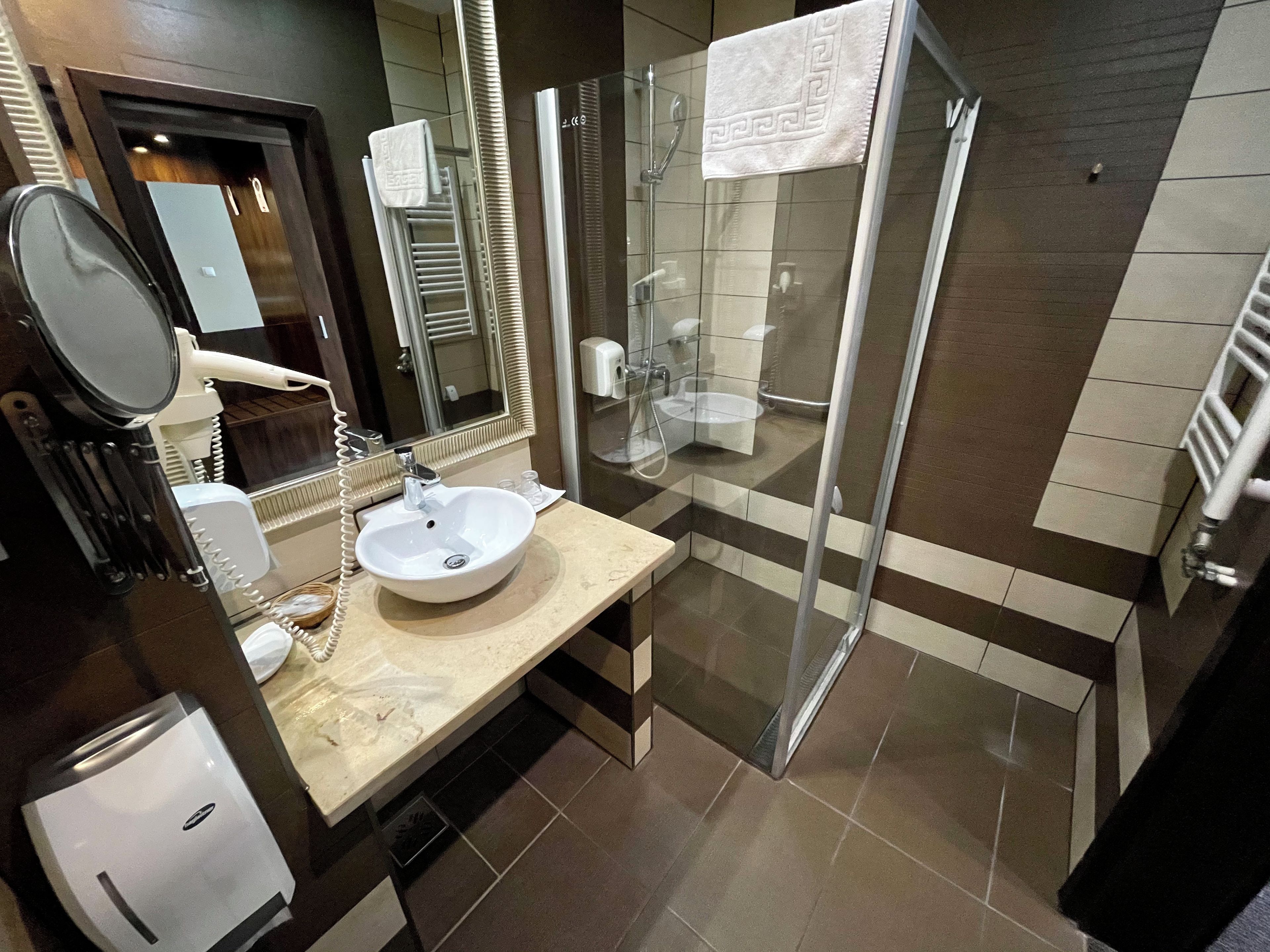 A modern bathroom with a large sink, a glass shower enclosure, and a mirror.
