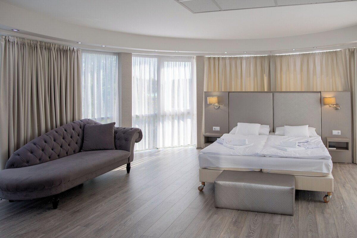 A modern hotel room with a large bed, a sofa, and a small table.