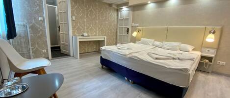 Habitación de hotel moderna con una cama grande, mesitas de noche, un escritorio y una silla.
