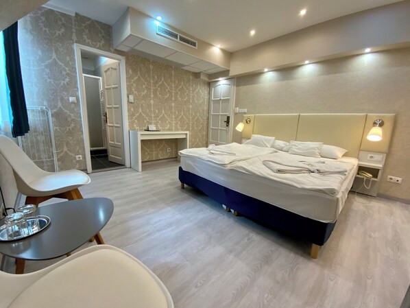 A modern hotel room with a large bed, bedside tables, a desk, and a chair. - Bastya Wellness Hotel (Miskolc)