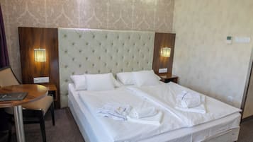 Quarto de hotel com uma cama grande, duas mesas de cabeceira, uma escrivaninha e uma cadeira.