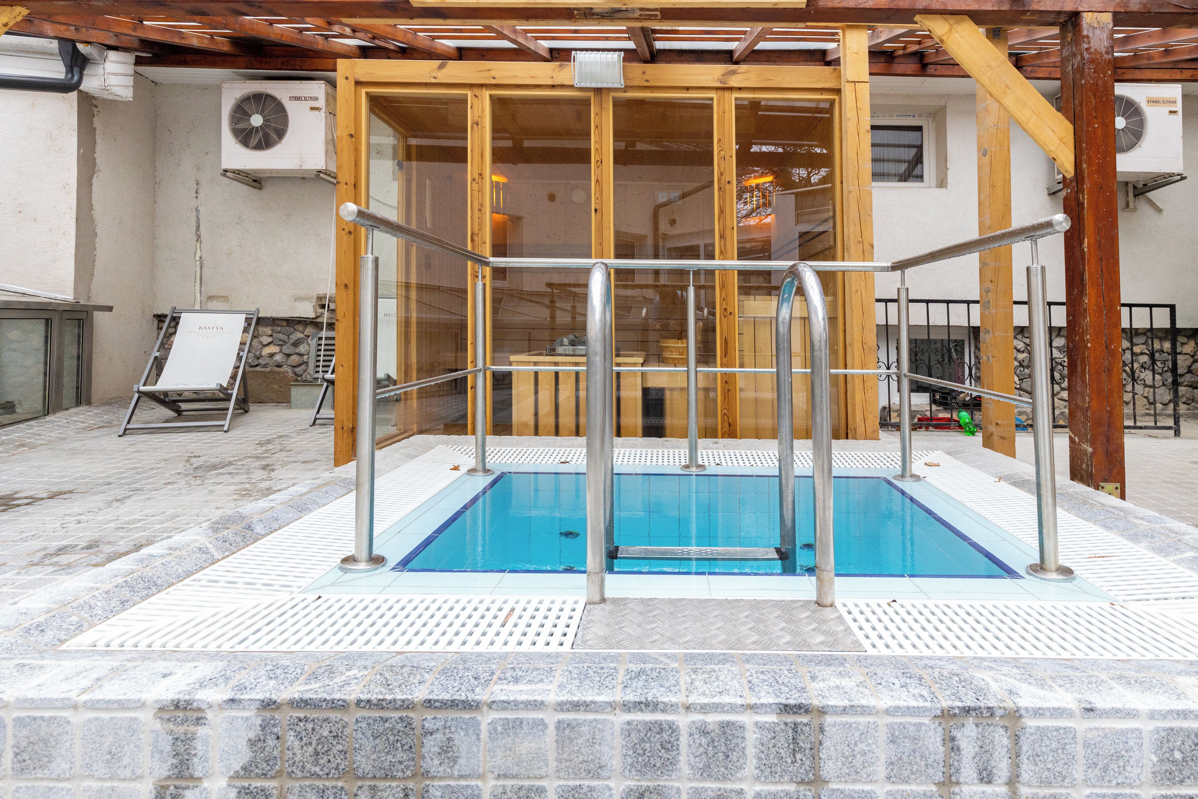 An indoor swimming pool with a wooden deck and a glass enclosure.