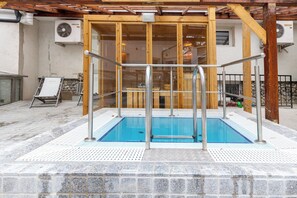 An indoor swimming pool with a wooden deck and a glass enclosure. - Bastya Wellness Hotel (Miskolc)