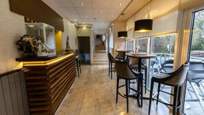 A modern bar area with a wooden counter, bar stools, and pendant lighting. - Bastya Wellness Hotel (Miskolc)
