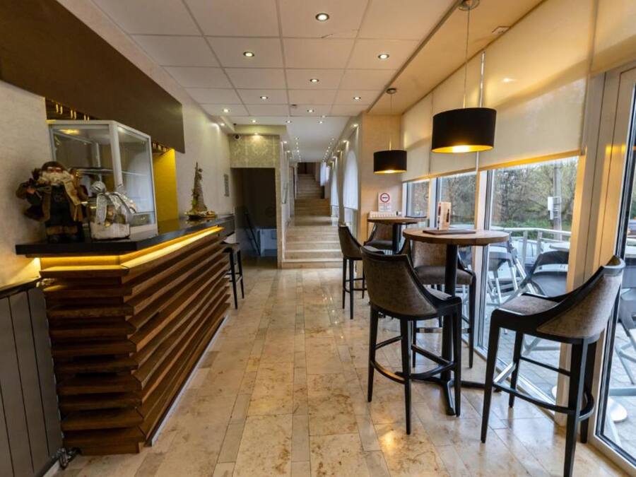 Un área de bar moderna con una barra de madera, taburetes y luminarias colgantes.